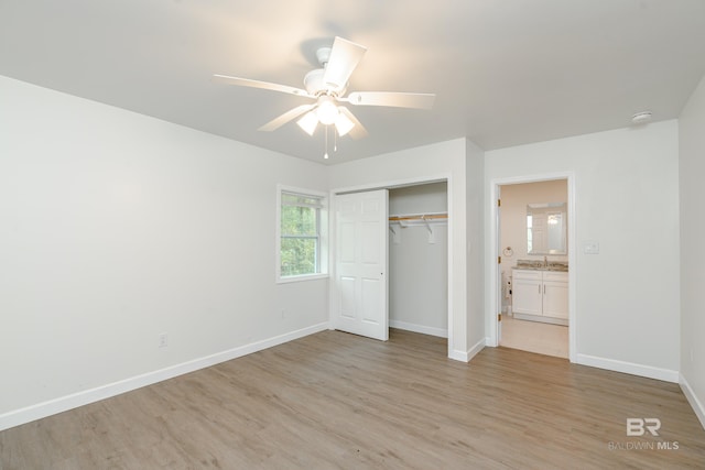 unfurnished bedroom with a closet, a sink, light wood-style flooring, and baseboards