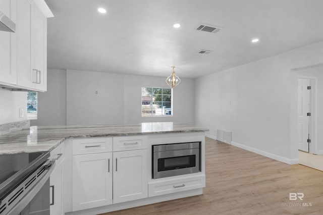 kitchen with white cabinets, stainless steel microwave, and visible vents