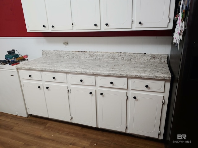 kitchen with white cabinets, dark hardwood / wood-style floors, and black refrigerator