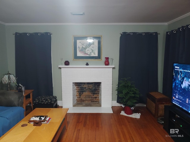 living room featuring hardwood / wood-style floors, ornamental molding, and a brick fireplace