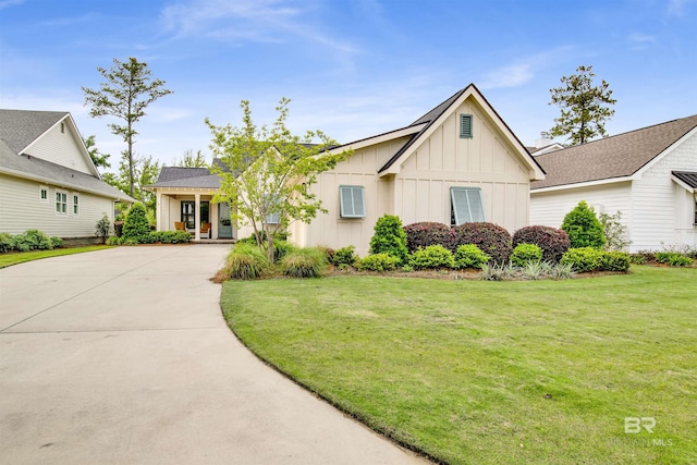 view of front of home featuring board and batten siding, concrete driveway, and a front lawn