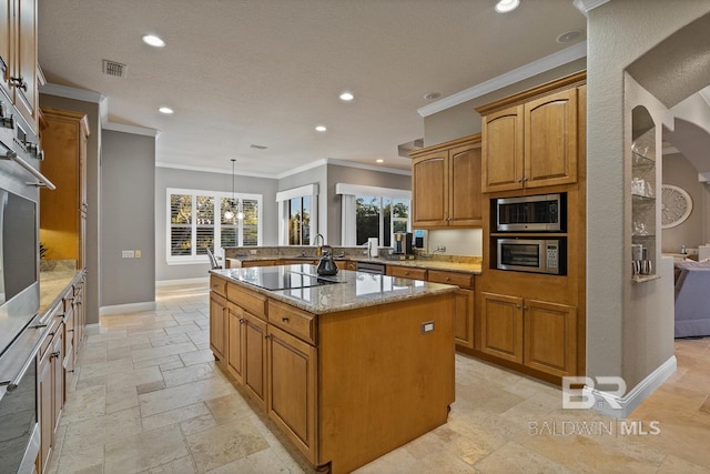 kitchen featuring appliances with stainless steel finishes, a center island, light stone countertops, and a wealth of natural light