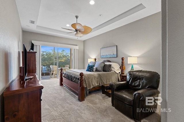 carpeted bedroom featuring ceiling fan, access to outside, and a tray ceiling