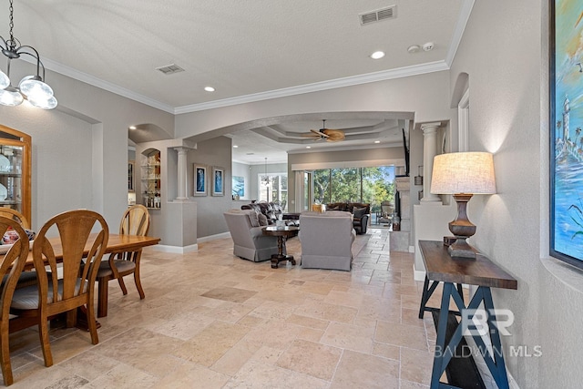 living room with ceiling fan, ornamental molding, a textured ceiling, ornate columns, and a tray ceiling