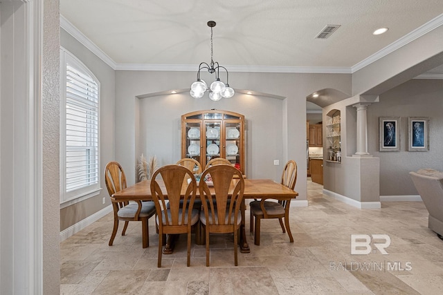 dining room with a chandelier, decorative columns, and ornamental molding