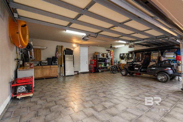 garage with white fridge and a garage door opener