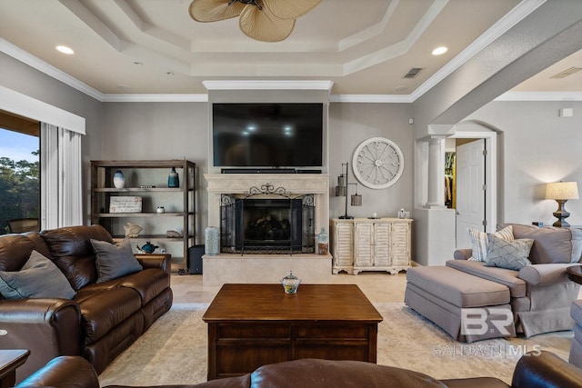 living room with a high end fireplace, a tray ceiling, ceiling fan, and ornamental molding