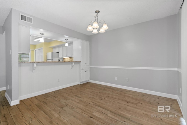 6701 Dickens Ferry Rd Unit 40, Mobile, AL 36608 - unfurnished dining area with light wood-style flooring, baseboards, and a chandelier
