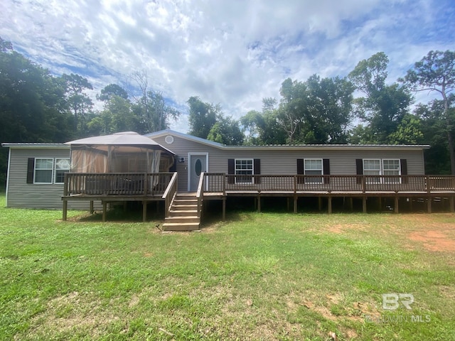 back of house featuring a gazebo, a wooden deck, and a lawn