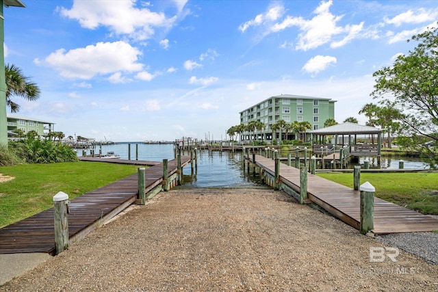 view of dock with a gazebo, a lawn, and a water view