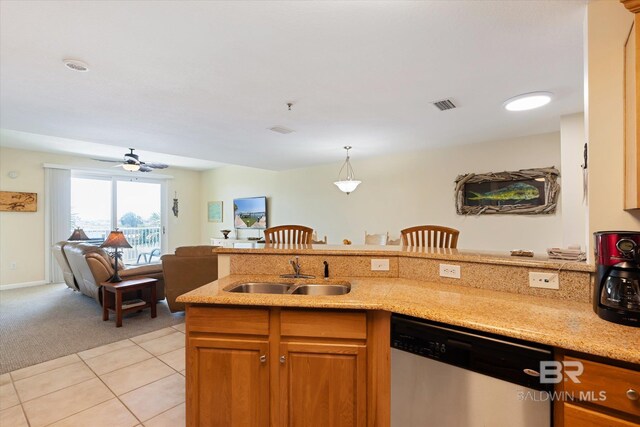 kitchen with light stone countertops, hanging light fixtures, sink, dishwasher, and light tile floors