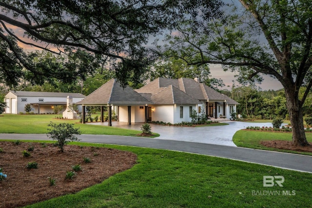 ranch-style home featuring curved driveway and a yard