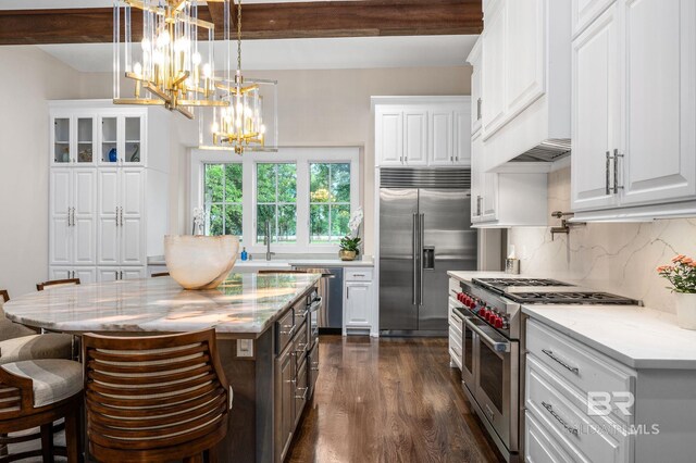 kitchen featuring decorative backsplash, dark wood-style flooring, high end appliances, white cabinets, and a notable chandelier