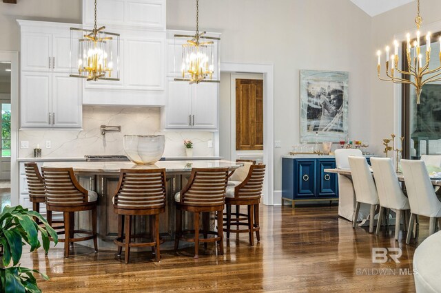 interior space featuring a high ceiling, dark wood finished floors, backsplash, and a notable chandelier