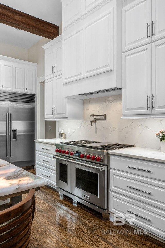 kitchen with beamed ceiling, high quality appliances, light countertops, white cabinets, and backsplash