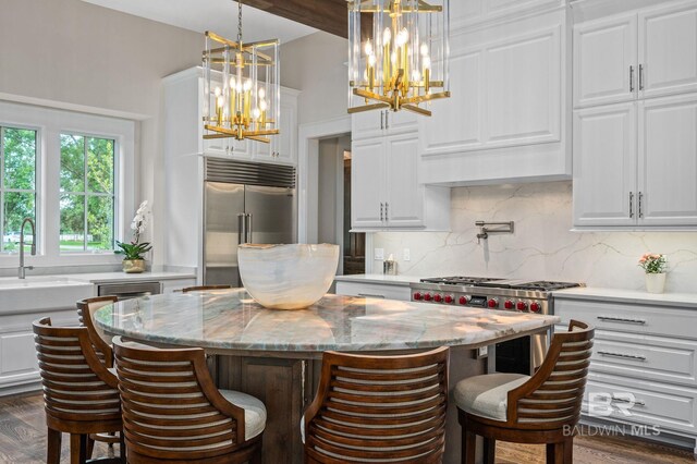 kitchen with high quality appliances, a notable chandelier, white cabinetry, and a center island