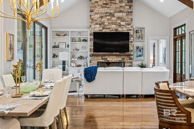 living area featuring wood finished floors, a stone fireplace, high vaulted ceiling, recessed lighting, and a chandelier