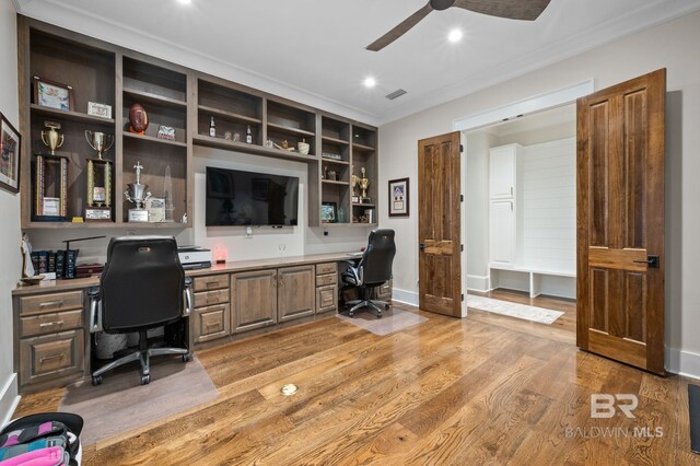 office featuring built in study area, crown molding, ceiling fan, and visible vents