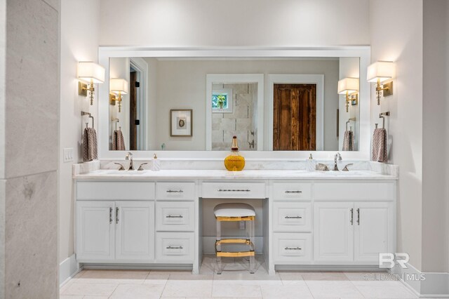 full bathroom with double vanity, tiled shower, and a sink