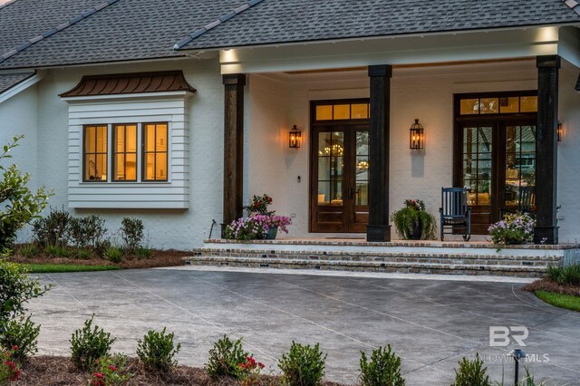 entrance to property featuring a standing seam roof, a shingled roof, and stucco siding