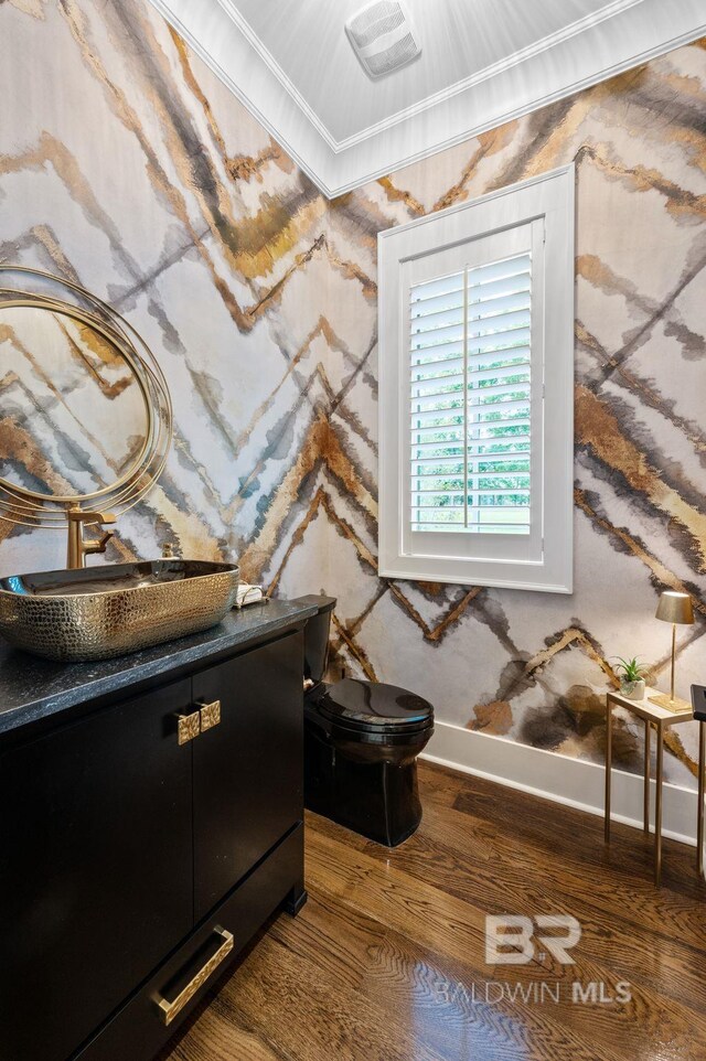 bathroom featuring vanity, ornamental molding, wood finished floors, toilet, and baseboards