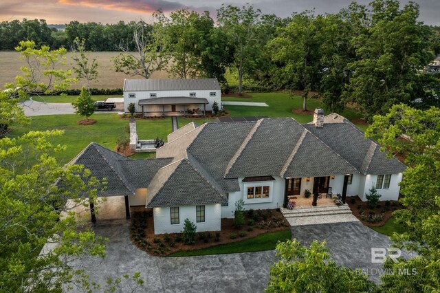 view of front facade featuring stucco siding, a shingled roof, and a front lawn