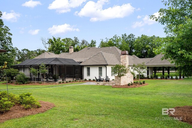 rear view of house with a yard, a patio, and a chimney