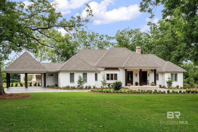 view of front facade with a chimney, an attached carport, driveway, and a front lawn