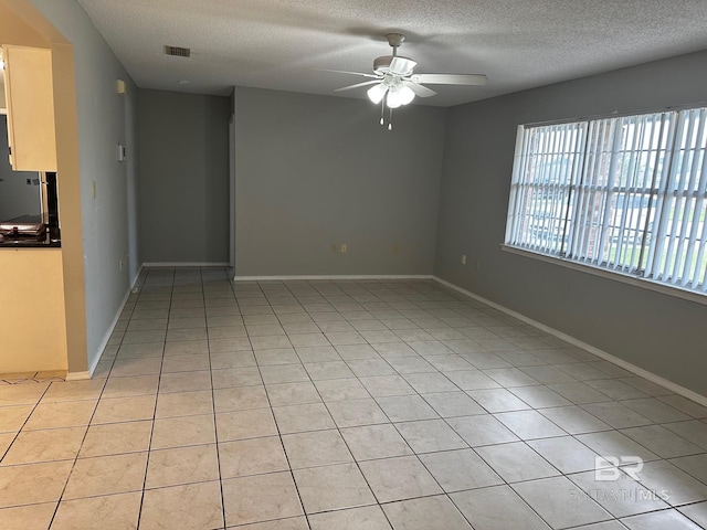 spare room featuring light tile patterned floors, a textured ceiling, and ceiling fan