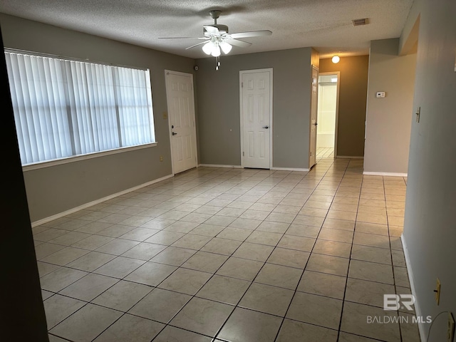 spare room with ceiling fan, a textured ceiling, and light tile patterned floors