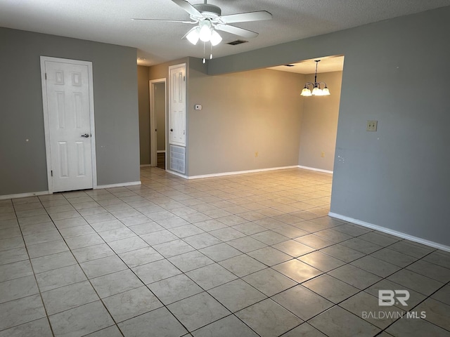 tiled empty room featuring ceiling fan with notable chandelier and a textured ceiling