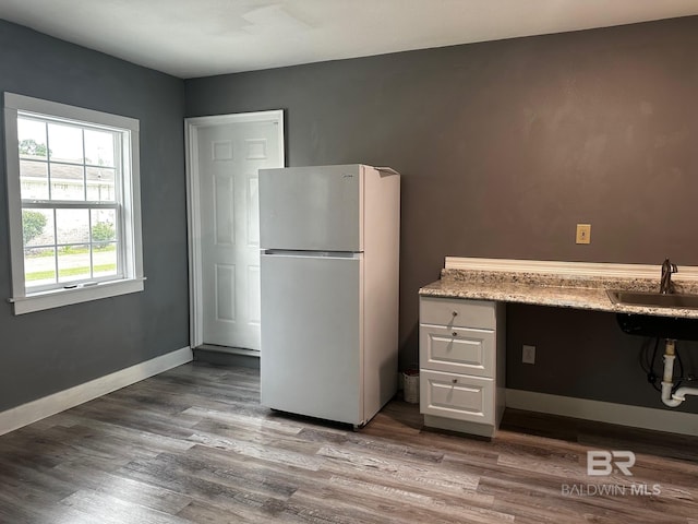 kitchen with white refrigerator, wood-type flooring, and sink