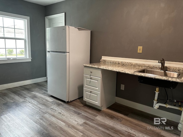 kitchen featuring white refrigerator, wood-type flooring, and sink