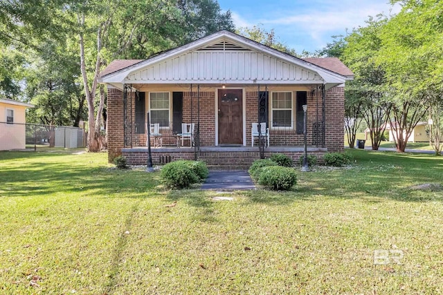 bungalow-style home featuring a porch, fence, a front lawn, and brick siding