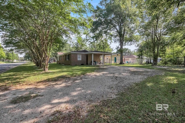 view of front of home featuring fence, a front lawn, and gravel driveway