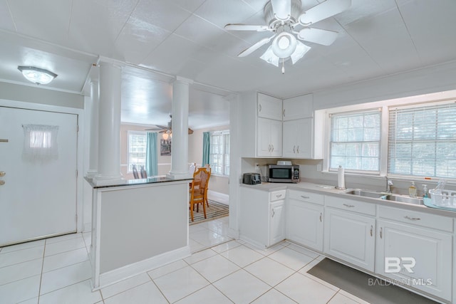 kitchen with a ceiling fan, stainless steel microwave, decorative columns, and white cabinetry