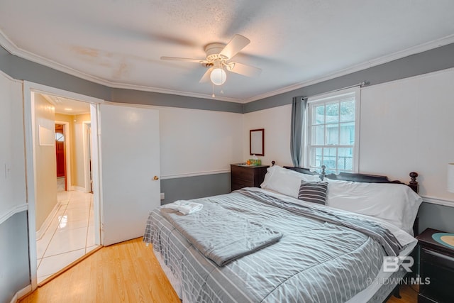 bedroom with crown molding, light wood-style floors, and ceiling fan