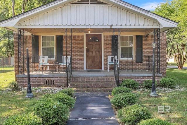 view of front facade featuring board and batten siding, brick siding, and covered porch