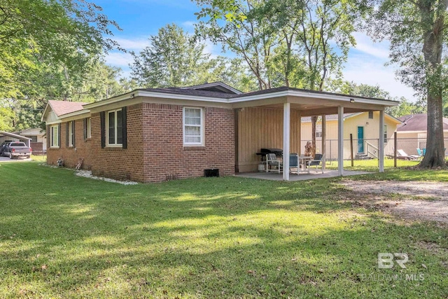 back of house featuring a yard, crawl space, fence, brick siding, and a patio area