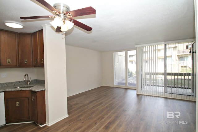 unfurnished living room with baseboards, dark wood-style flooring, a sink, and a wall of windows