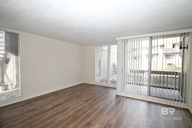 spare room with a textured ceiling, floor to ceiling windows, and dark wood-type flooring