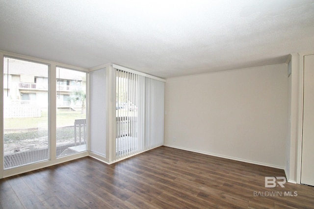 unfurnished room featuring dark wood-style floors, baseboards, and a textured ceiling