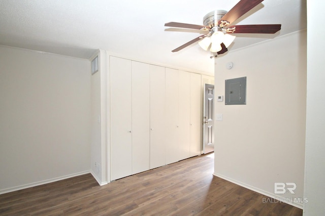 unfurnished bedroom with dark wood-style floors, a closet, ceiling fan, electric panel, and baseboards