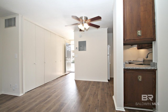 interior space featuring a sink, a ceiling fan, visible vents, electric panel, and dark wood-style floors