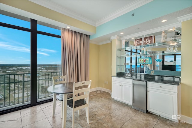 kitchen featuring a wealth of natural light, crown molding, white cabinetry, and light tile floors