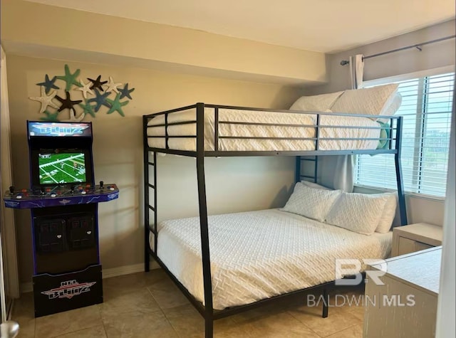 tiled bedroom featuring baseboards and multiple windows