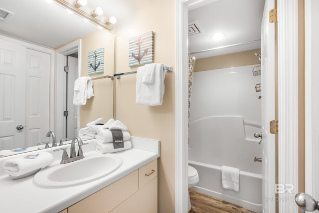 full bathroom featuring shower / washtub combination, vanity, visible vents, toilet, and wood finished floors