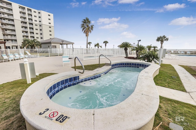 community pool with a patio area and fence