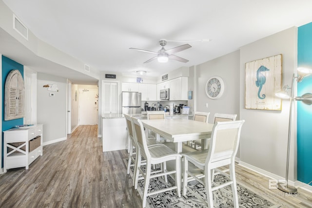 dining room with light wood-type flooring, ceiling fan, baseboards, and visible vents