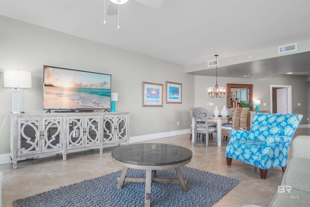 tiled living room with ceiling fan with notable chandelier